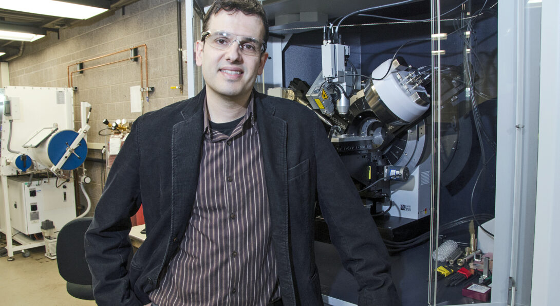 Prof. Cabana stands by an X-ray diffractometer, an instrument that characterized energy storage materials.