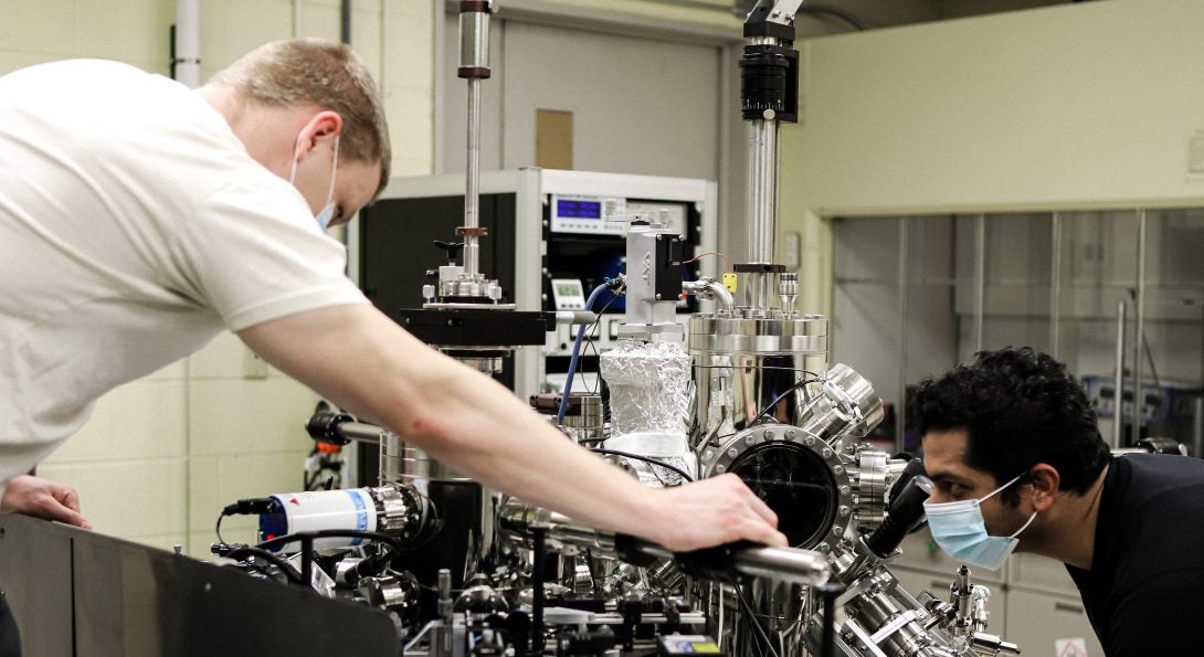 Sayantan Mahapatra and Jeremy Schultz examine an ultrahigh vacuum system.